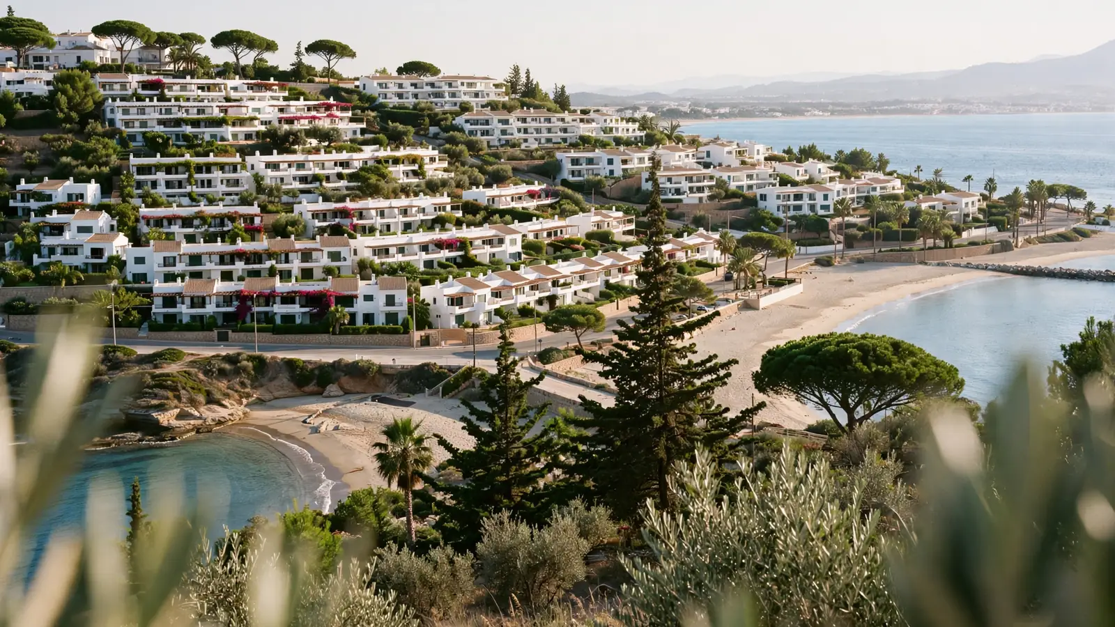 The terraced residential hillside at Calahonda on Mijas Costa, with white low-rise homes stepping down among pines toward two small beaches