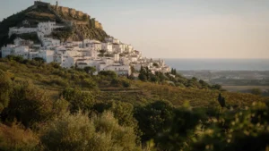 The white village of Casares cascading down its hillside beneath the Moorish castle, with terraced vineyards below and the coast in the distance