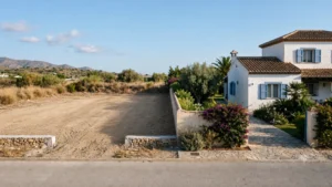 En ryddet, afsat byggegrund direkte op ad en etableret bolig med moden beplantning på Costa del Sol