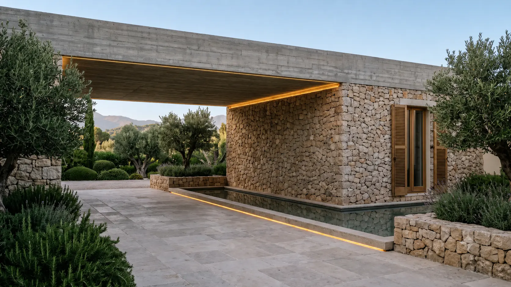 Ankomstgården til en nutidig luksusbolig mellem Marbella og Benahavís med stenfacade, vandspejl og moden beplantning