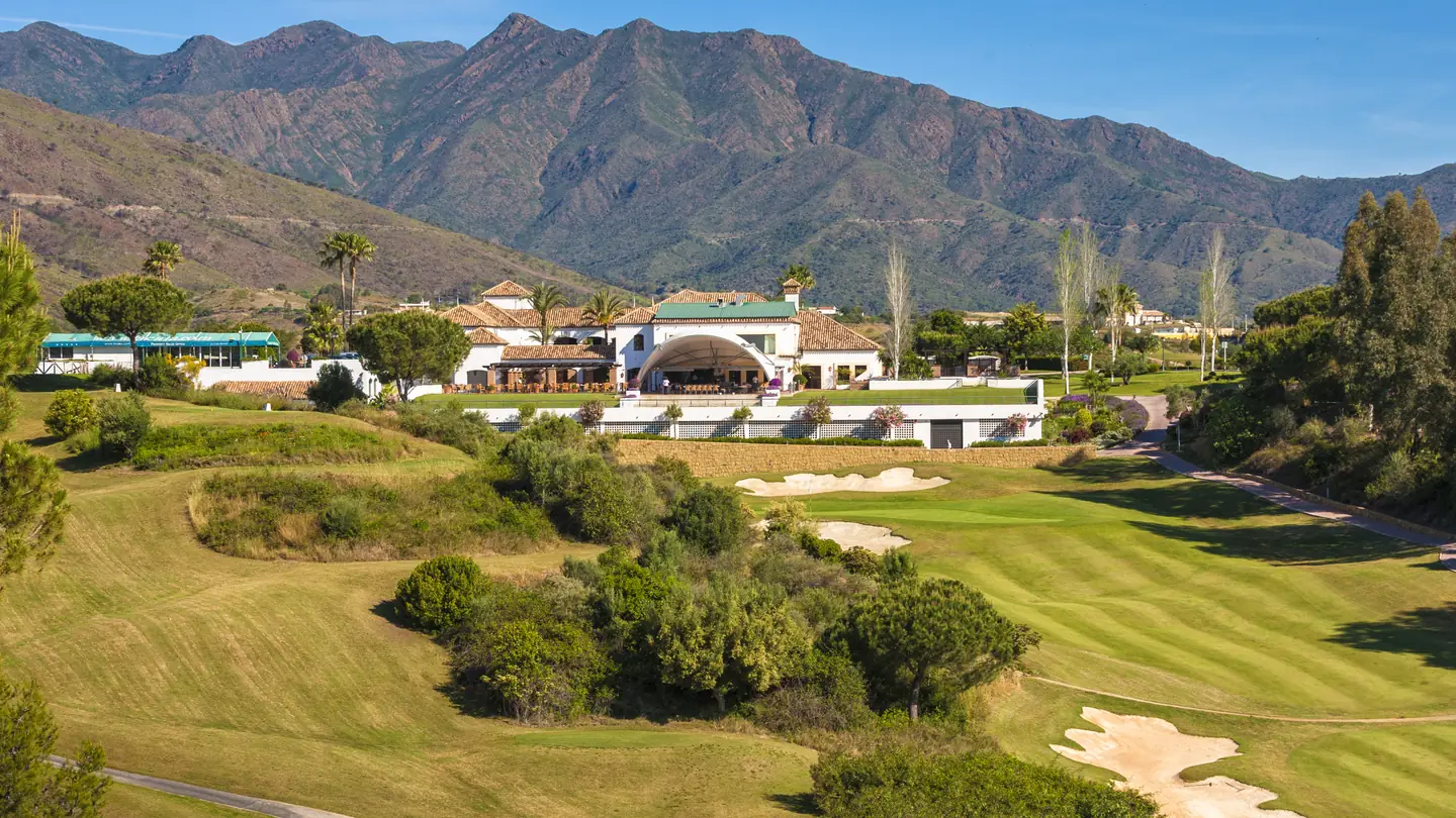 The La Cala Golf estate in the Sierra de Mijas, with fairways and bunkers below the clubhouse and the mountain ridge rising behind