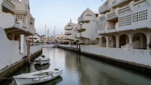 A water channel at Puerto Marina in Benalmadena, lined with the marina's distinctive white sculptural apartment architecture and small moored boats