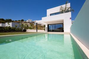 Modern white villa with a pool and glass balustrades on the Costa del Sol under a clear blue sky